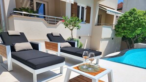 A poolside area with two lounge chairs and a small table with glasses.