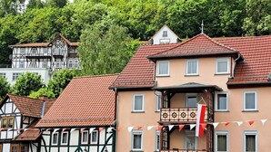 A traditional European building with a balcony, a street sign, and a flag. - Haus Lieberum, Gemütliche Ferienwohnung Direkt am Kurpark (Bad Sooden-Allendorf)