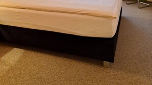 A hotel room with a bed, a nightstand, a lamp, a chair, a television, and a window with curtains. - Haus Lieberum, Gemütliche Ferienwohnung Direkt am Kurpark (Bad Sooden-Allendorf)