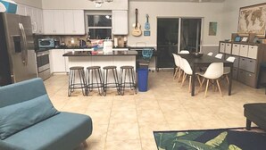 Une cuisine moderne dotée d’un îlot central, de tabourets de bar et d’un coin repas avec des chaises.