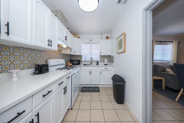 A compact kitchen with white cabinets, a gas stove, and a tiled backsplash. - 5 mins to UofA - Pet Friendly Retreat! Fenced Yard (Tucson)