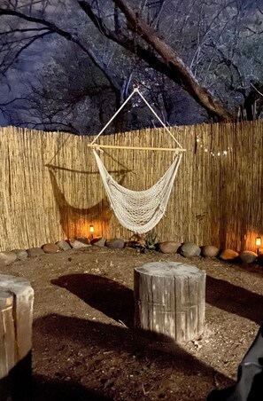 A hammock hanging from a wooden structure in an outdoor setting with a bamboo wall and rocks. - 5 mins to UofA - Pet Friendly Retreat! Fenced Yard (Tucson)