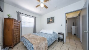 Ein Schlafzimmer mit Bett, Schminktisch, Deckenventilator und einem Bild an der Wand.