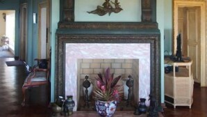 Una habitación amplia con techo alto, chimenea y candelabro.