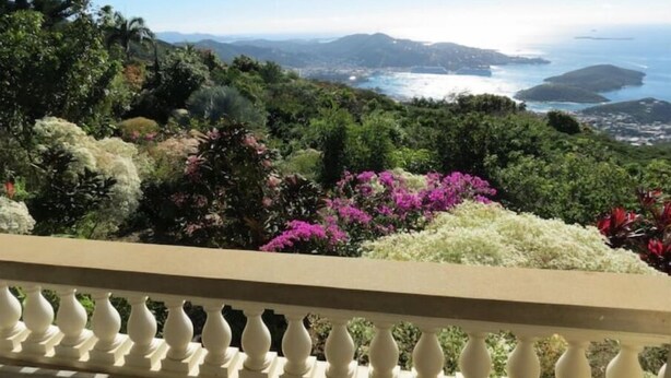 Un balcón con vistas a un paisaje costero, que incluye montañas y el mar.