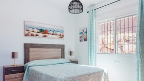 A bedroom with a bed, bedside tables, a painting, and a window with curtains. - Vacation Home "Sunset El Tejar" with Mountain View, Private Pool & Wi-Fi (Almogia)