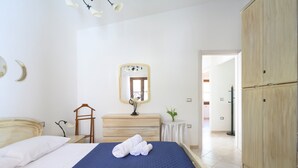 Een slaapkamer met een bed, een dressoir, een spiegel en een kledingkast.