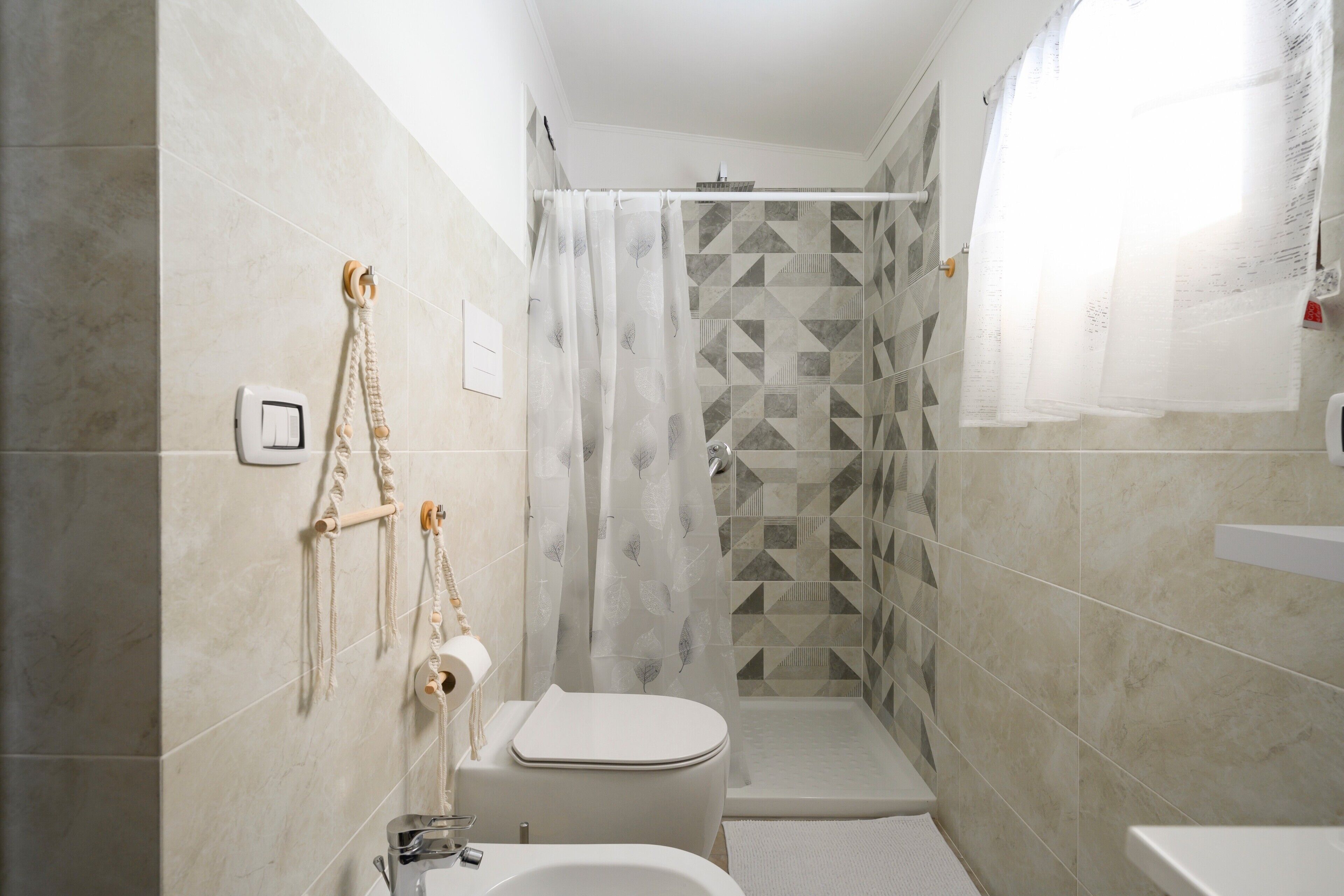A bathroom with a toilet, shower, and sink.
