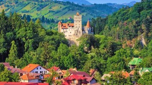 A castle surrounded by lush greenery and a village with red-roofed houses. - Studio 4 - 5 Strada Scărlătescu (București)