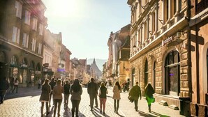 A cobblestone street lined with historic buildings, a clear sky, and people walking. - Studio 4 - 5 Strada Scărlătescu (București)