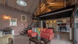 A spacious living area with a red sofa, a wooden coffee table, and a staircase leading to an upper level. - Villa Manolia (Πρέβεζα)