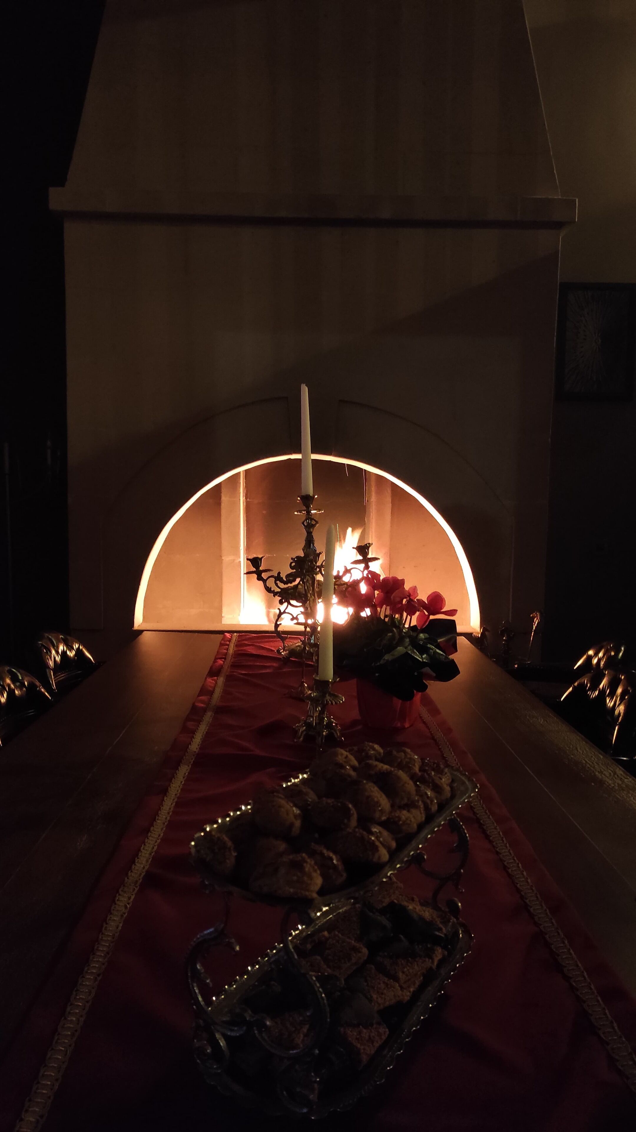 A cozy room with a fireplace, a candelabra, and a tray of cookies.