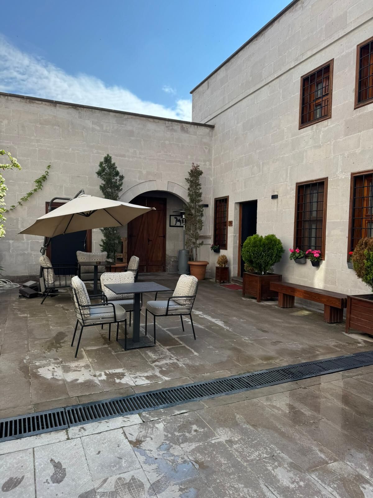 Un cortile con tavolo e sedie, un'area lounge coperta e piante in vaso.