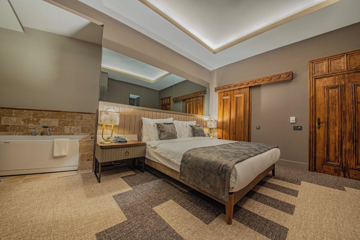 Une chambre à coucher moderne avec un grand lit, une coiffeuse intégrée, une baignoire et une armoire en bois.