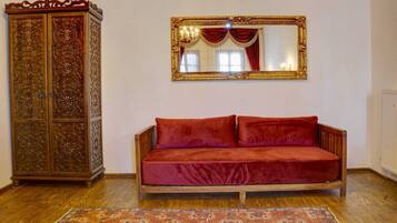 A room with a wooden cabinet, a red velvet sofa, and a large mirror on the wall.