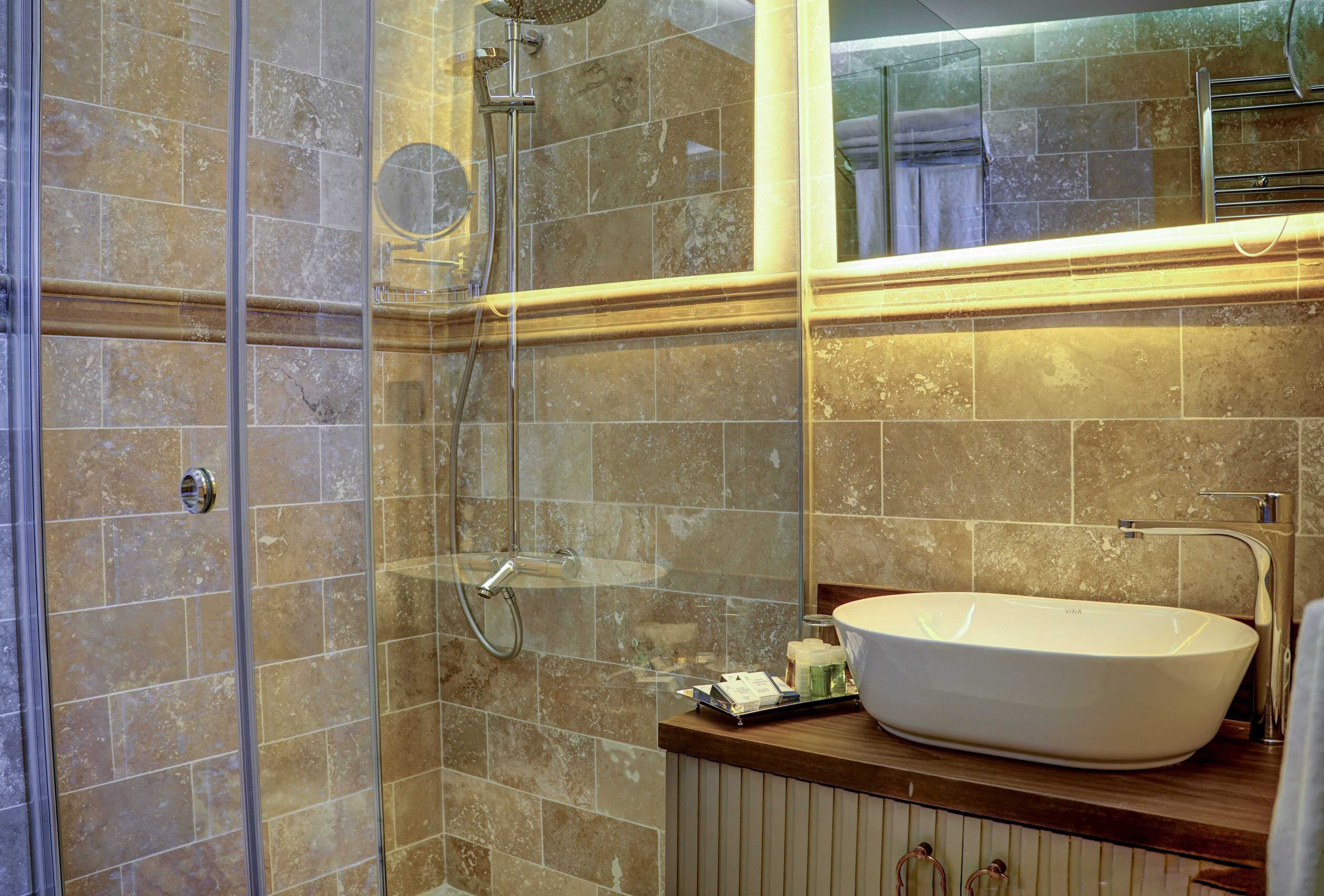 A bathroom with a glass-enclosed shower, a white sink, and a mirror above the sink.