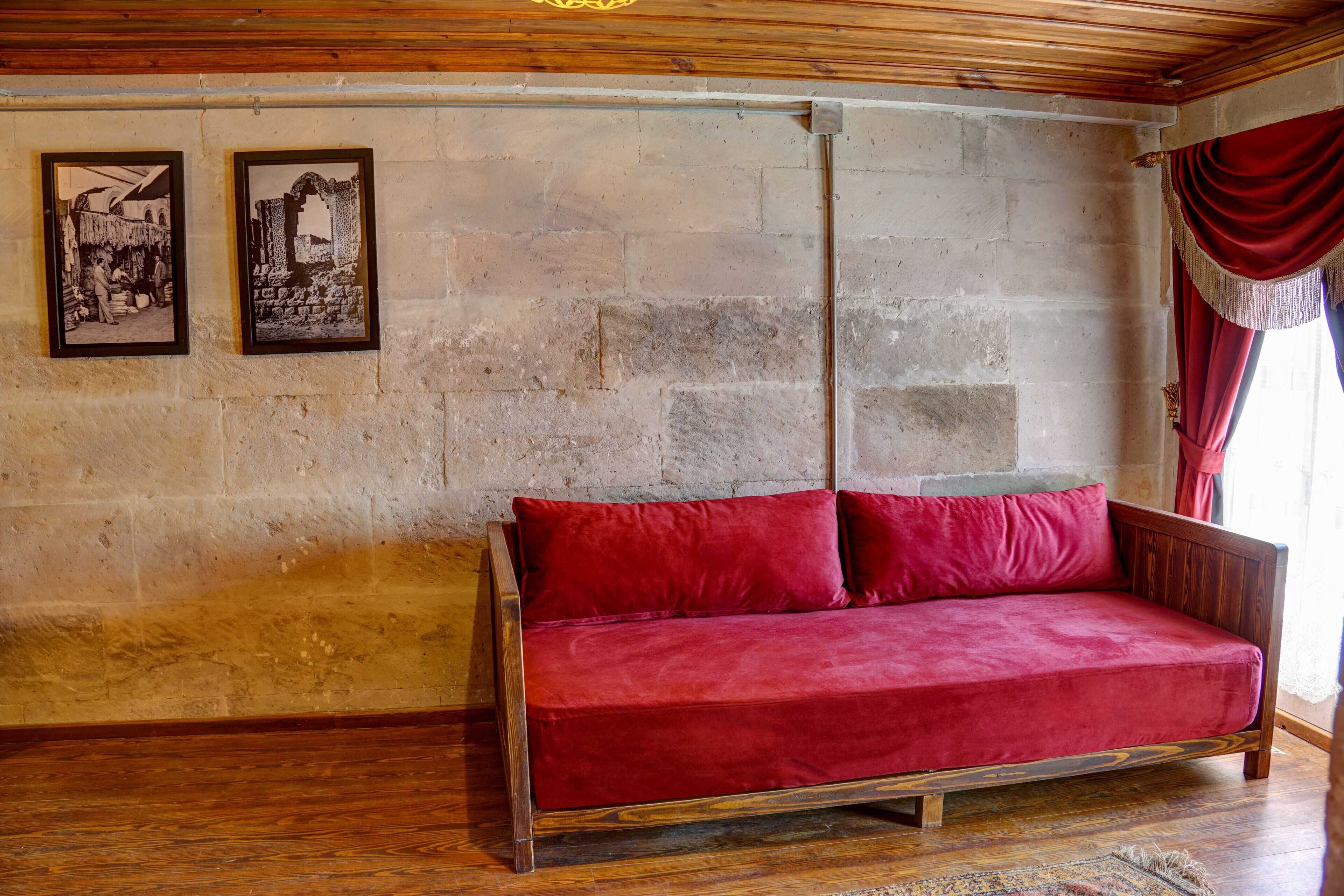 Ein Zimmer mit einem roten Sofa, zwei gerahmten Bildern an der Wand und Holzboden.