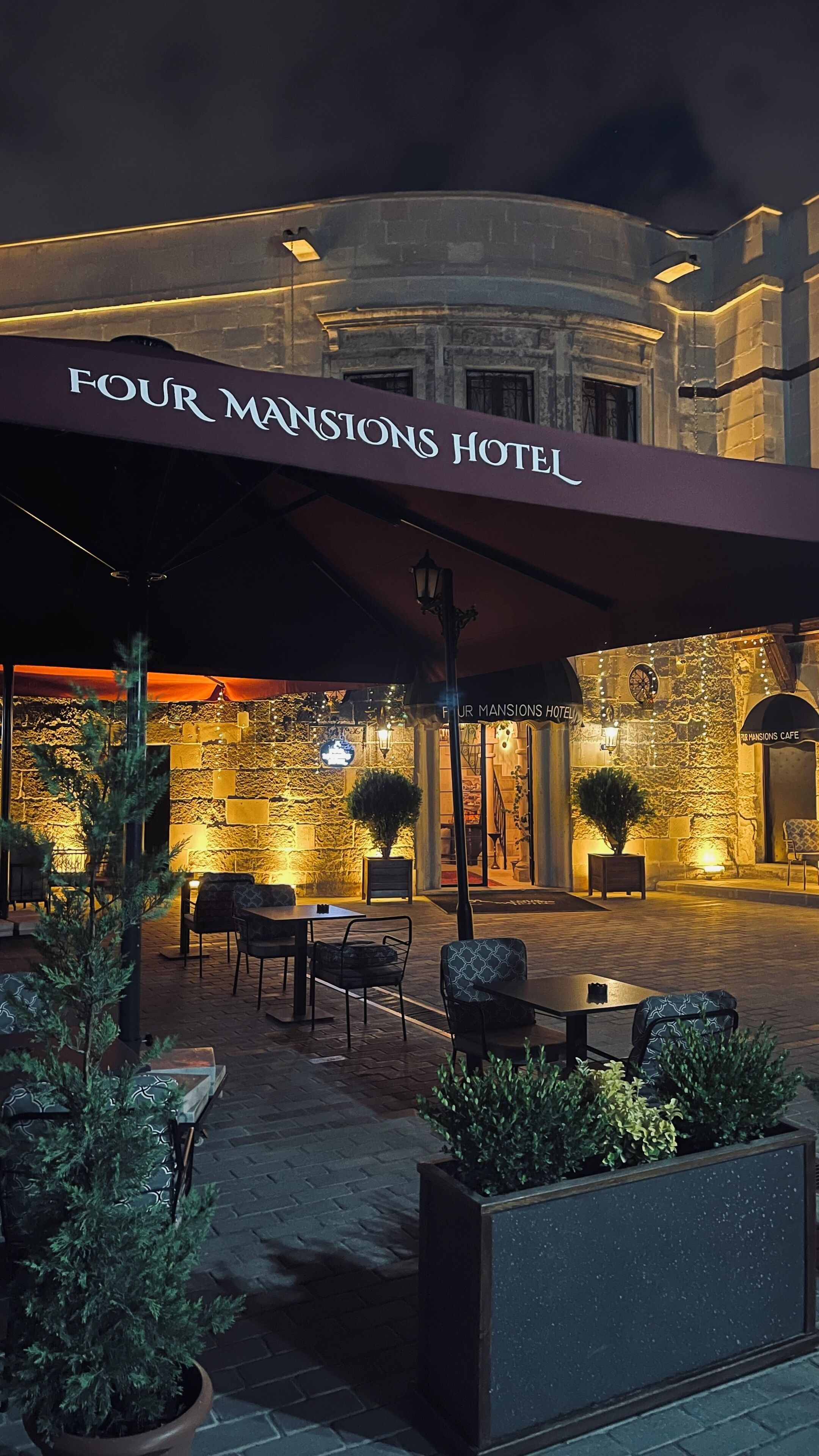 The exterior of Four Mansions Hotel with outdoor seating and a stone facade.
