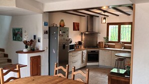 A kitchen with a central island, a stove, and a sink. There are wooden chairs and a table. - Villa Provençale aux Portes D'avignon (Villeneuve-lès-Avignon)