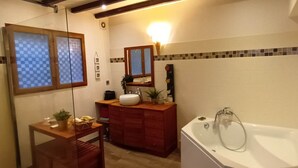 A bathroom with a wooden vanity, a large bathtub, and a window with checkered blinds. - Villa Provençale aux Portes D'avignon (Villeneuve-lès-Avignon)