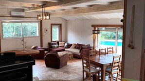 A spacious living area with a piano, a dining table with chairs, a sofa, and a large window offering a view of greenery. - Villa Provençale aux Portes D'avignon (Villeneuve-lès-Avignon)