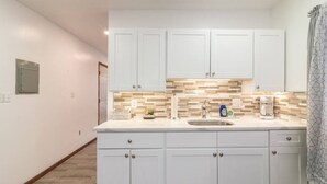 A kitchen with white cabinets, a tiled backsplash, and a sink. - Quiet Apt with Coffee Bar, 1/2 Mile to West Point! (Highland Falls)