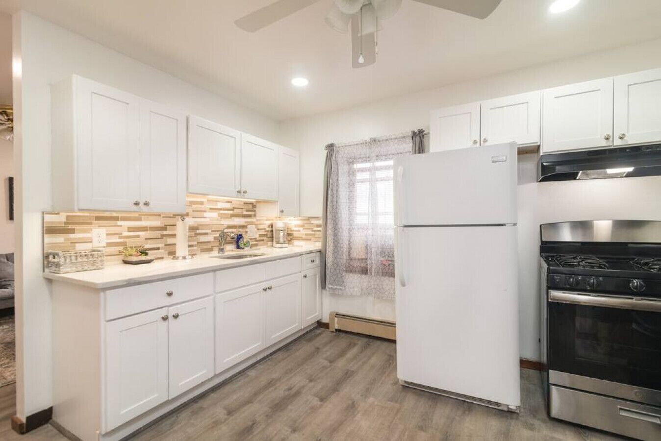 A modern kitchen with white cabinets, a stainless steel oven, and a tiled backsplash.