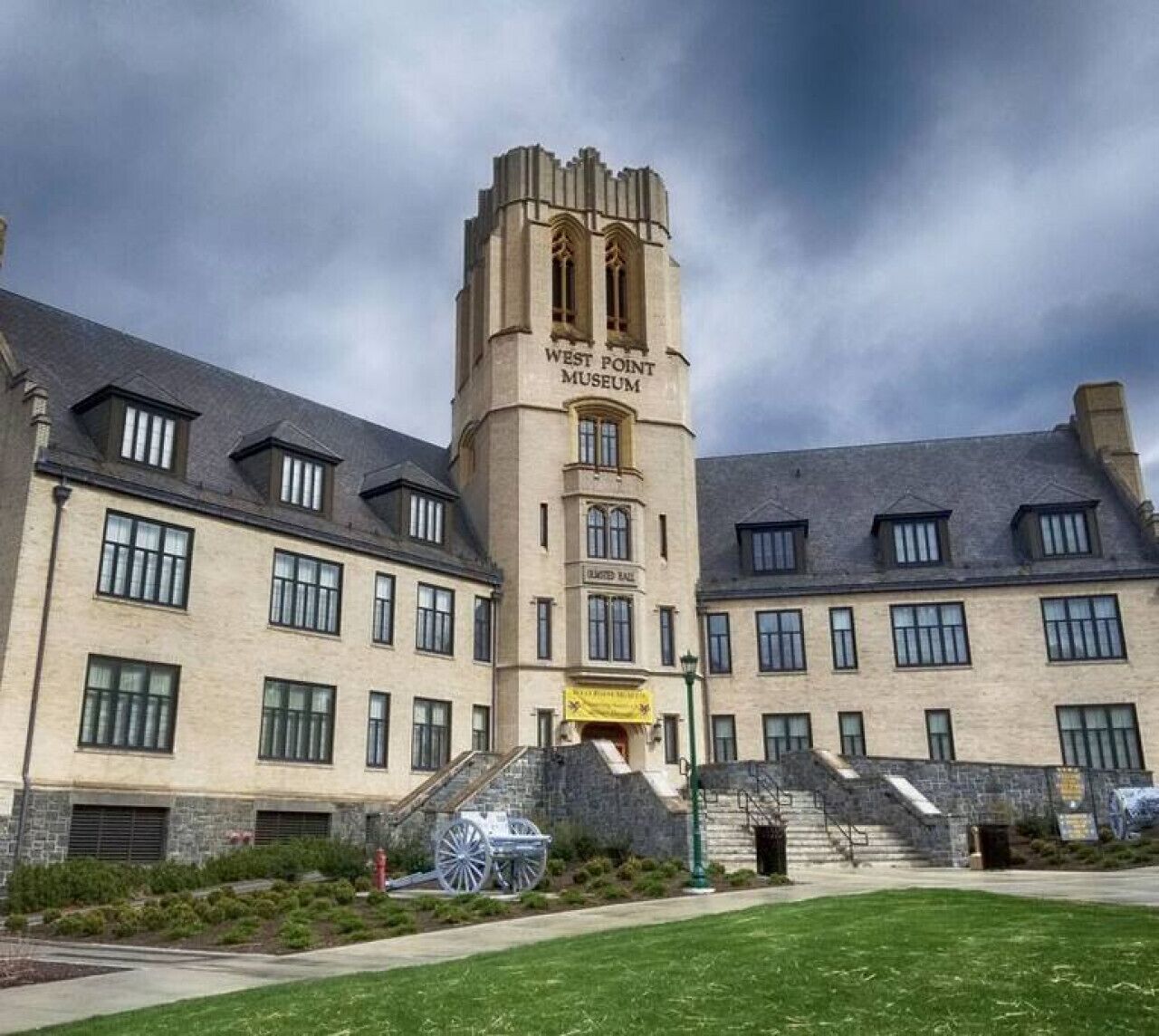 A historic building with a central tower labeled 'West Point Museum,' featuring a traditional architectural style with multiple windows and a stone facade.