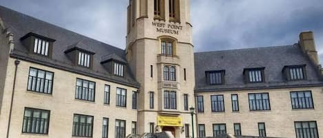 A historic building with a central tower labeled 'West Point Museum,' featuring a traditional architectural style with multiple windows and a stone facade.