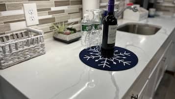 A kitchen counter with a wine bottle, glasses, and a decorative mat.