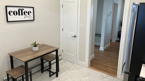 A kitchen with a dining table, a refrigerator, and a door leading to another room. - Local Artist Inspired | Walk to WestPoint + King Bed (Highland Falls)