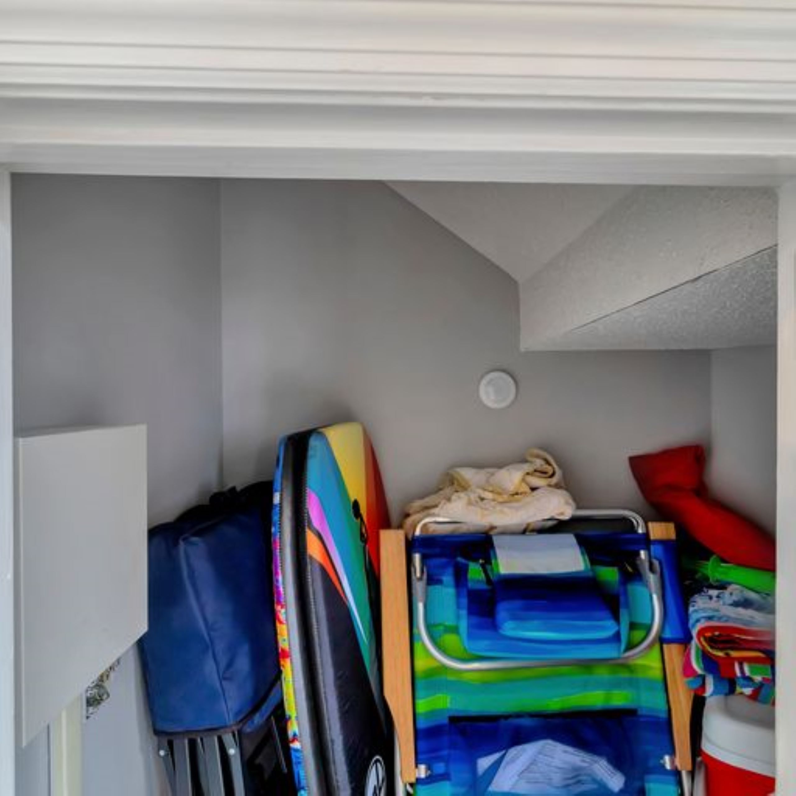 A storage area with a suitcase, a colorful backpack, and a blue and green bag.
