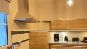 Una cocina moderna con armarios de madera, una campana extractora de acero inoxidable y una encimera con cafetera, tostadora y hervidor.