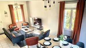 Una sala de estar moderna con un sofá, una mesa de comedor preparada para cuatro personas y un televisor.