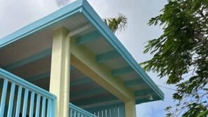 En bygning med en lyse gul facade og blå detaljer, herunder en balkon med blå gelændere.