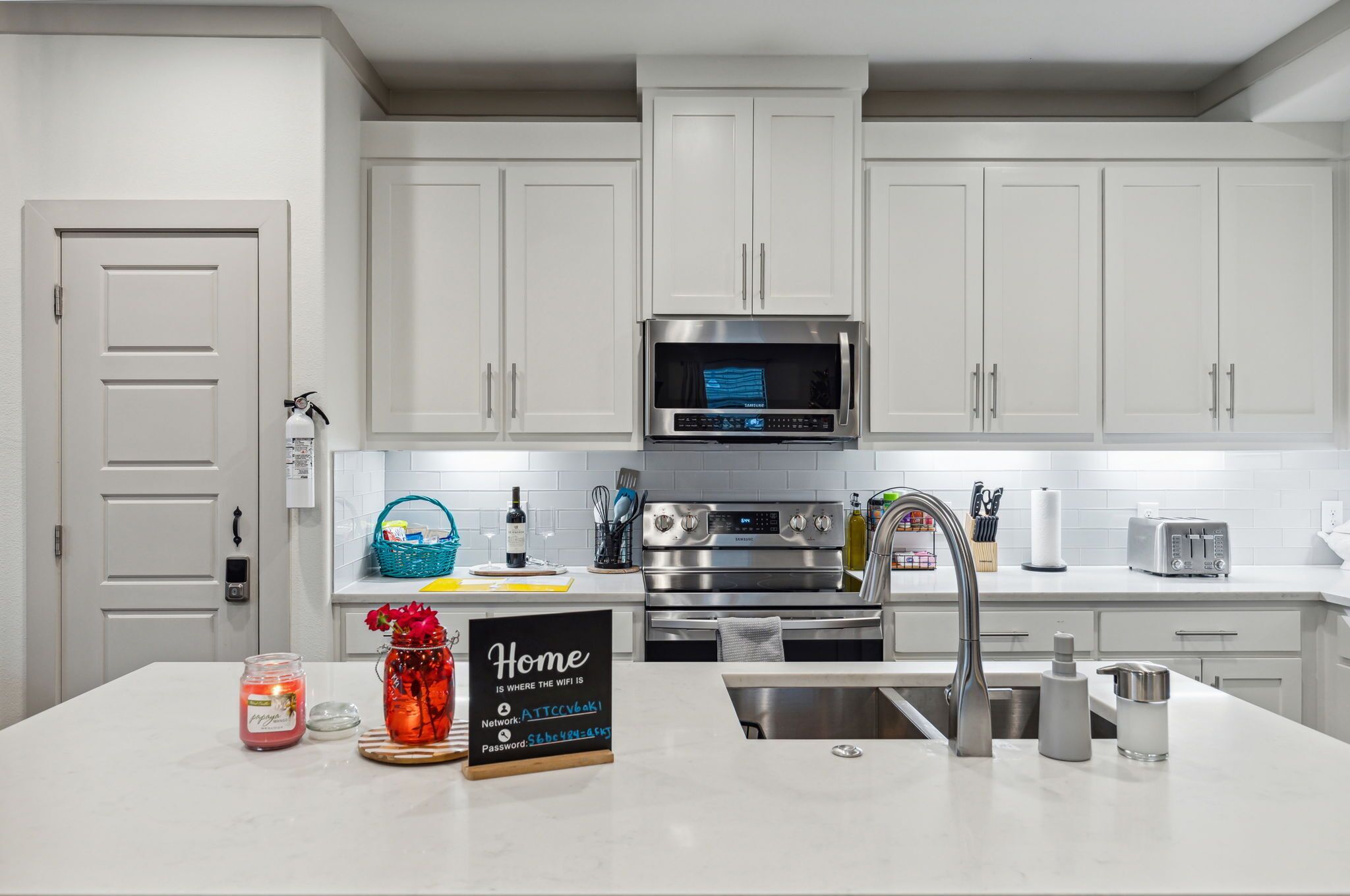 Una cocina moderna con gabinetes blancos, electrodomésticos de acero inoxidable y una isla central con lavamanos.