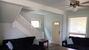 A living room with two black sofas, a wooden coffee table, a patterned rug, a staircase, and a ceiling fan. - Beach House on the shores of Lake Michigan Near downtown Sheboygan (Sheboygan)