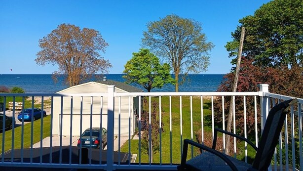A balcony with a view of the sea, a white fence, and a house in the background. - Beach House on the shores of Lake Michigan Near downtown Sheboygan (Sheboygan)