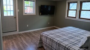 A bedroom with a bed, a television mounted on the wall, and two windows. - Beach House on the shores of Lake Michigan Near downtown Sheboygan (Sheboygan)