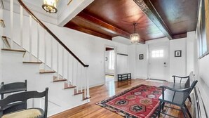 A spacious room with a wooden staircase, a large rug, and a bench.