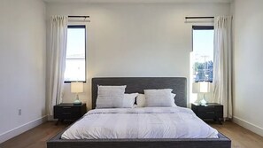 Relax in this serene bedroom with a large bed and two nightstands, each with a lamp, and enjoy the view from the large window.