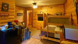 Ein gemütliches Blockhaus-Zimmer mit Etagenbett, Schreibtisch inklusive Computer und einer kleinen Küchenzeile.