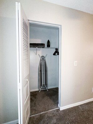 A walk-in closet with a hanging rack, shelves, and a shoe rack.