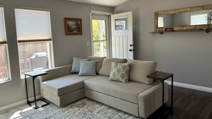 A living room with a sectional sofa, a small side table, a ceiling fan, and a door with a window. -  Eastside Costa Mesa, close to Disneyland, beaches.
1.5 miles to JWA airport. (Costa Mesa)