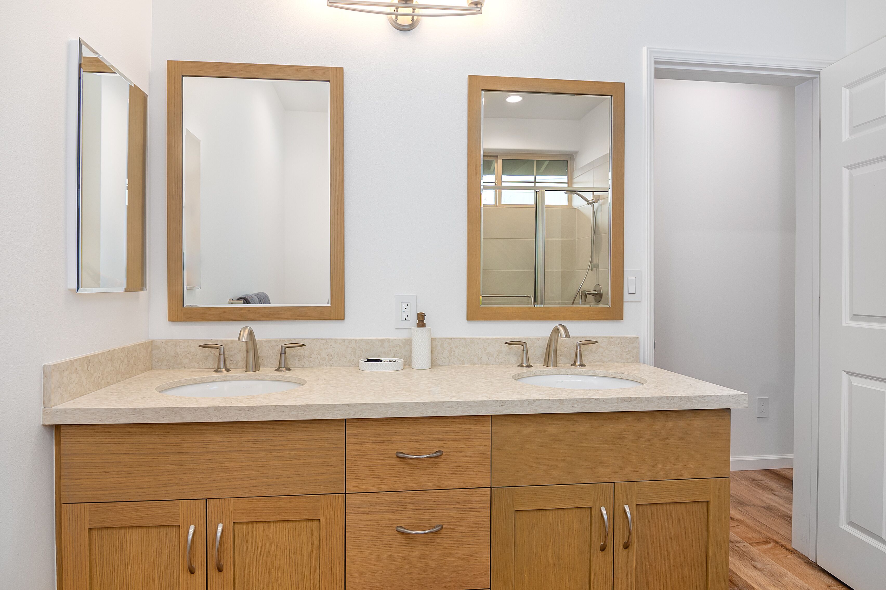 A bathroom with two sinks, wooden cabinets, and two mirrors.
