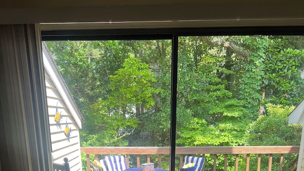 Eine Terrasse mit Tisch und Stühlen, eine Glastür, die in einen Garten führt.