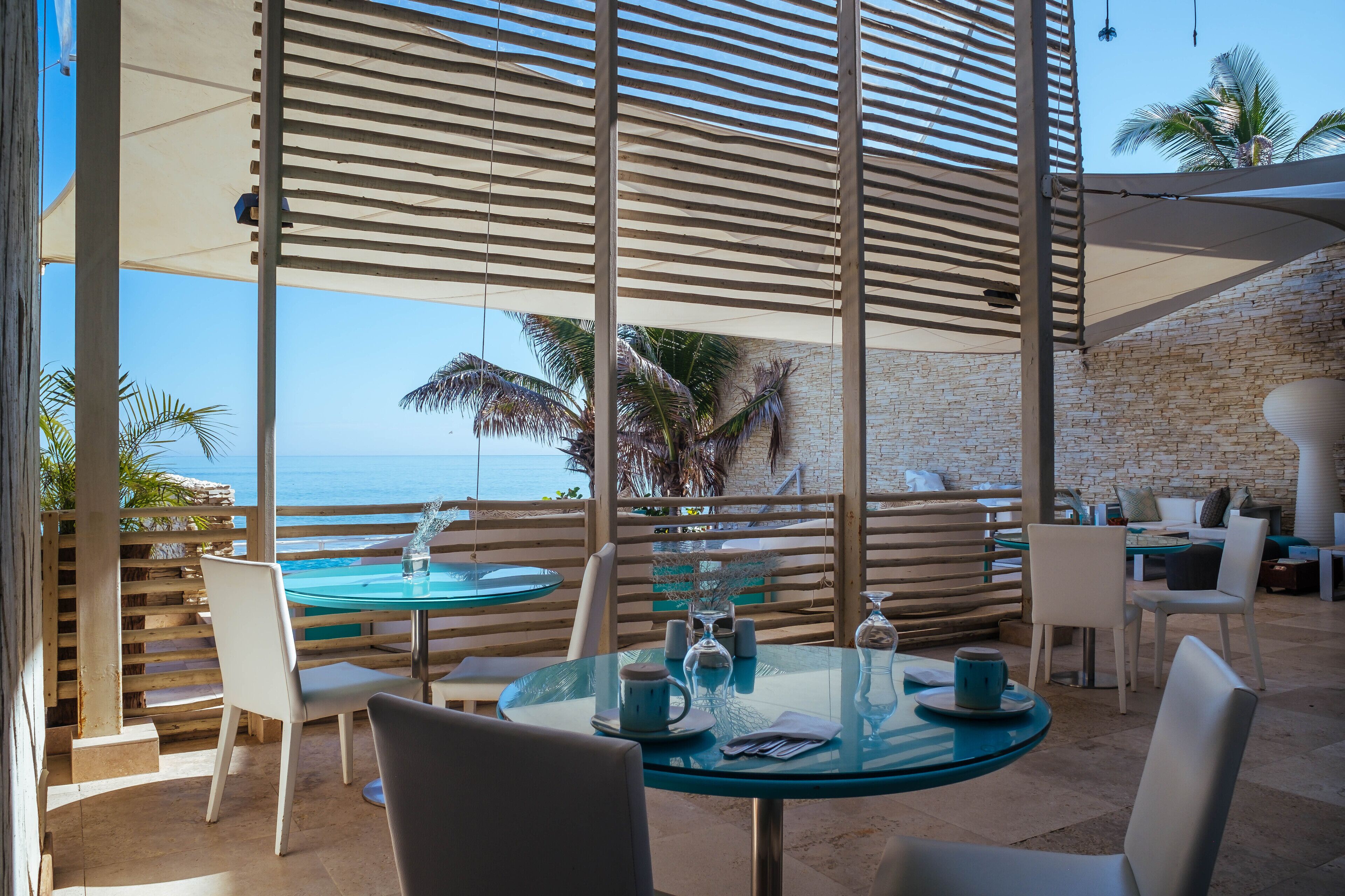 A glass table with chairs and a view of the ocean.