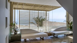 Un intérieur moderne avec une grande fenêtre donnant sur une plage, un banc et une cloison en verre.