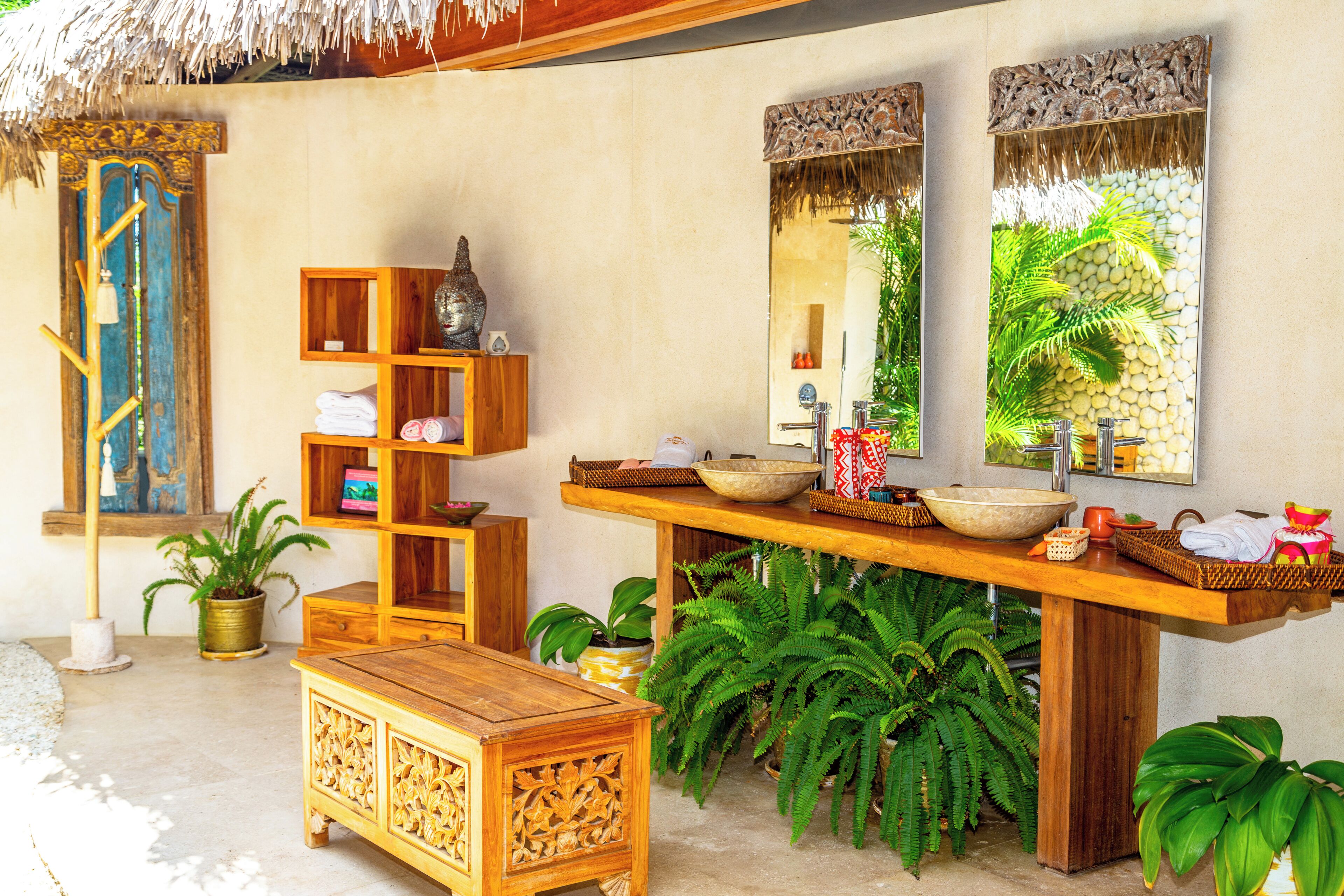 A bathroom with a wooden vanity, a large mirror, and a thatched roof.