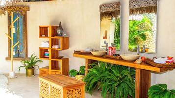 A bathroom with a wooden vanity, a large mirror, and a thatched roof.